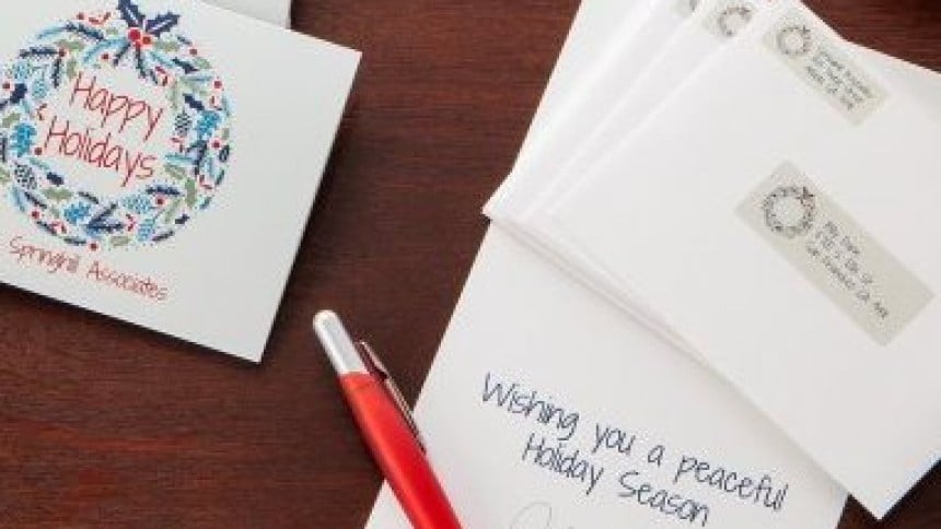 Na sliki sta dve beli božični voščilnici, naslovljeno pismo ter rdeč kulij.