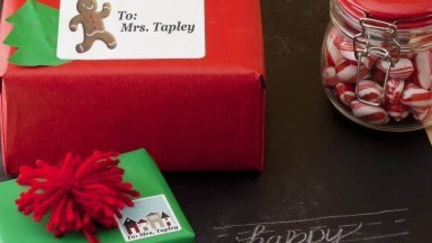 Na sliki sta dve božični darili. Eno je zavito v rdeč papir in na njem je etiketa z imenom in majhna zelena smreka, drugo pa je zeleno in ima tudi etiketo z imenom ter rdečo pentljo. Zraven je še steklen kozarec poln rdeče belih sladkarij.