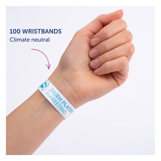 Slika prikazuje roko osebe, ki nosi zapestnico z napisom '100 WRISTBANDS Climate neutral', na kateri je natisnjeno 'JULIEN PLATTER MARKETING'.