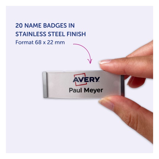 Slika prikazuje značko z imenom iz nerjavečega jekla z napisom 'Avery Paul Meyer'. Značko drži roka osebe. Ozadje je svetlo vijolično, dimenzije značke pa so 68 x 22 mm.