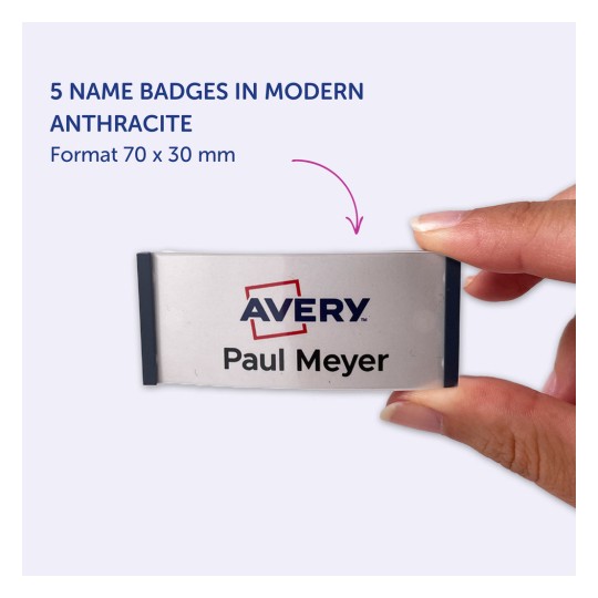 Slika prikazuje osebo, ki drži priponko z imenom 'Avery Paul Meyer' in prikazuje pet priponk v sodobni antracitni barvi, dimenzij 70 x 30 mm.