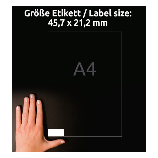 Slika prikazuje roko poleg nalepke formata A4 z dimenzijami 45,7 x 21,2 mm. Ozadje je temno, kar poudarja vidljivost nalepke in roke.