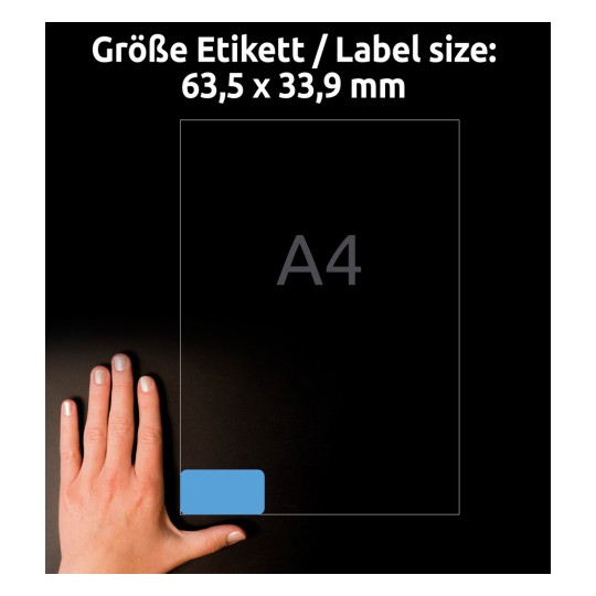 Slika prikazuje roko poleg lista papirja formata A4, z dimenzijami označenimi za nalepko, ki meri 63,5 x 33,9 mm. Ozadje je temno, kar poudarja roko in velikost nalepke.