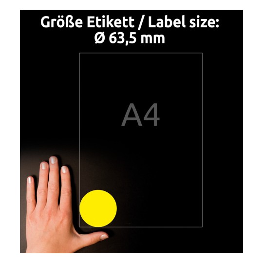 Slika prikazuje roko na črni površini, ki drži dokument z oznako 'A4', na katerem je velika rumena okrogla nalepka v spodnjem desnem kotu. Besedilo zgoraj označuje velikost nalepke Ø 63,5 mm.