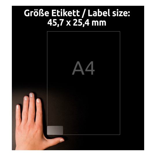 Slika prikazuje roko, ki drži nalepko ali dokument z dimenzijami 45,7 x 25,4 mm, poleg velikosti črke A4, na temnem ozadju.