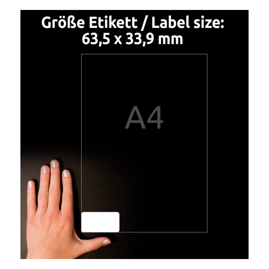 Slika prikazuje roko, ki leži poleg prazne nalepke velikosti 63,5 x 33,9 mm na ozadju papirja velikosti A4. Del z nalepko je označen, z ustreznimi dimenzijami prikazanimi v jasni pisavi.