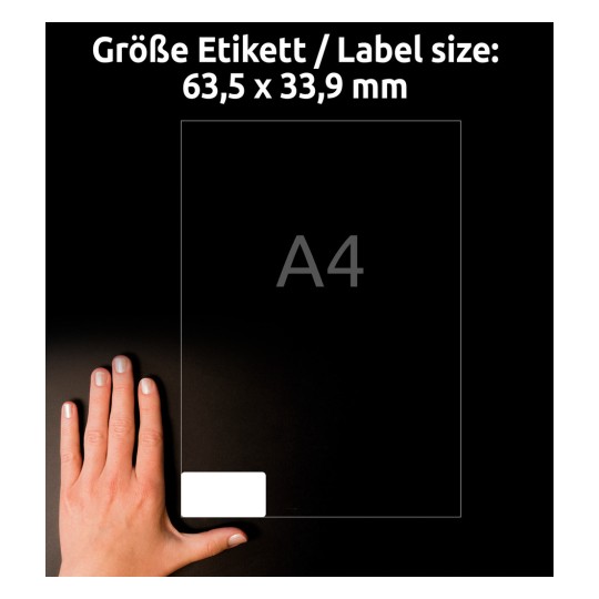 Slika prikazuje roko, ki drži prozoren list z oznako 'A4'. Vključuje besedilo, ki označuje velikost nalepke: 63,5 x 33,9 mm, na temnem ozadju.