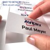 Slika prikazuje roko, ki drži kartico z oznakami 'Avery' in 'Paul Meyer', kar pomeni, da jo je enostavno odstraniti, saj ima gladke robove. V ozadju je videti več kartic.