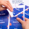 Slika prikazuje roke, ki ločujejo odsek iz visokokakovostnega natisnjenega papirja z imeni in prikazanimi vlogami. Ozadje ima živahno zasnovo z modrimi in rdečimi elementi.