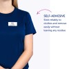 Slika prikazuje žensko, ki nosi mornarsko modro majico z nalepko z imenom. Na nalepki piše ime 'B. Carlos' in naziv 'Direktorica marketinga', spremlja pa jo opis uporabnosti nalepke.
