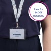 Slika prikazuje osebo, ki nosi temno majico in trakec z identifikacijsko kartico, na kateri piše 'MELINA DOPPER' in 'Oblikovalka.' Trakec ima pisano rožnati vzorec. V besedilnem oblačku na sliki piše 'Idealno za IMETNIKE KARTIC.'