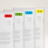 Slika prikazuje vrsto prosojnih plastičnih map, ki so razporejene drugo ob drugi, vsaka je označena za označevanje oddelkov, organiziranih po razponu črk: A-D v rdeči, E-H v zeleni, I-R v modri in S-Z v rumeni barvi. Vsebujejo natisnjene dokumente, čeprav je besedilo delno zastrto.