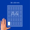 Roka ob listu A4, ki prikazuje mrežo pravokotnikov nalepk velikosti 30 × 50 mm?
