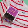Slika prikazuje oblačilni žig z napisom 'Clothing Stamp', nameščen na majico s črtami, ki ima rdeče črte. Majica ima oznako z napisom 'LAURA BAYARD'. Žig je znamke 'Avery'.